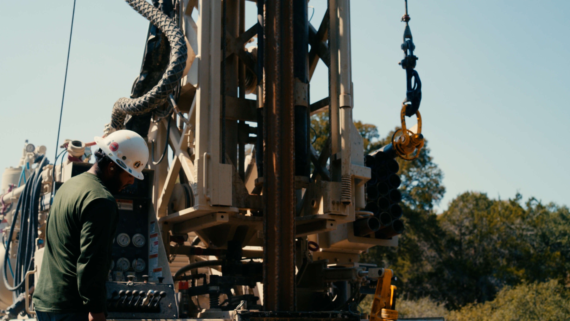 Operator's hand on rig controls at dusk